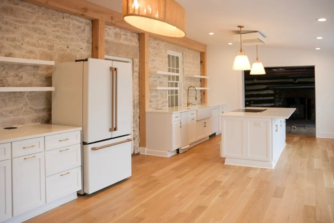 Modern kitchen with white cabinets, travertine backsplash, island, and wood accents