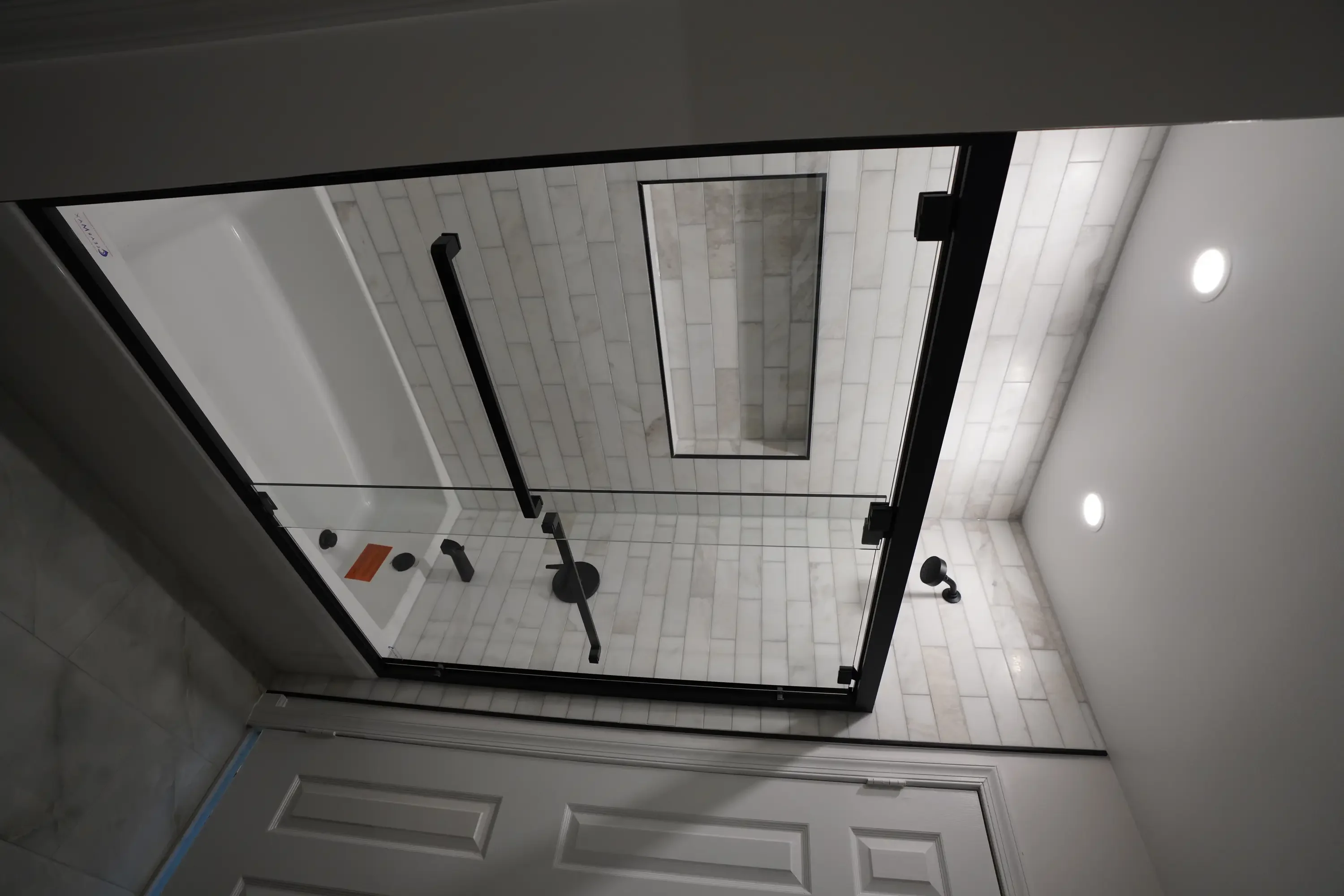 Modern bathroom shower with white subway tile, black frame, and frameless glass door