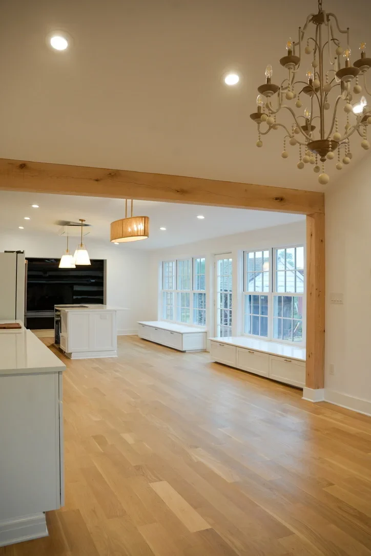 Open concept kitchen and living room with timber beam, hardwood floors, and large windows