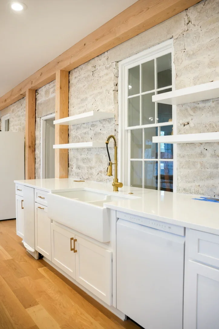 Modern kitchen with white cabinets, travertine backsplash, and wooden beam accents
