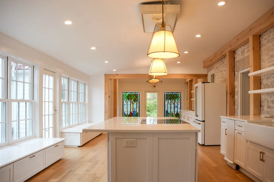 Bright kitchen with white cabinetry, center island, pendant lights, and stained glass doors