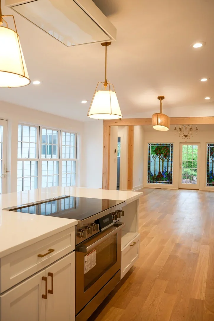 Modern kitchen with white cabinetry, island cooktop, pendant lights, and hardwood floors