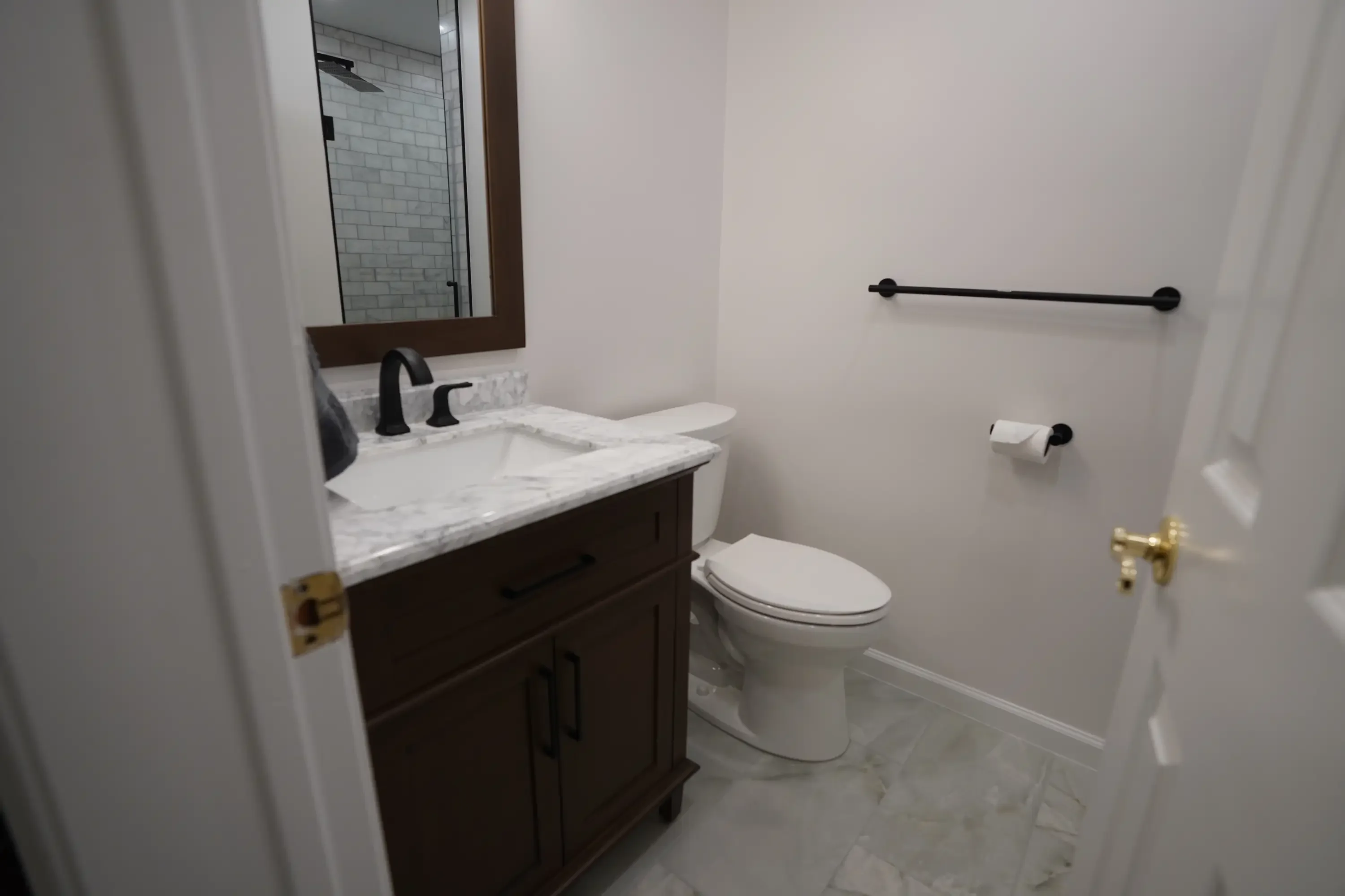 Renovated bathroom with dark wood vanity, marble countertop, and subway tile shower