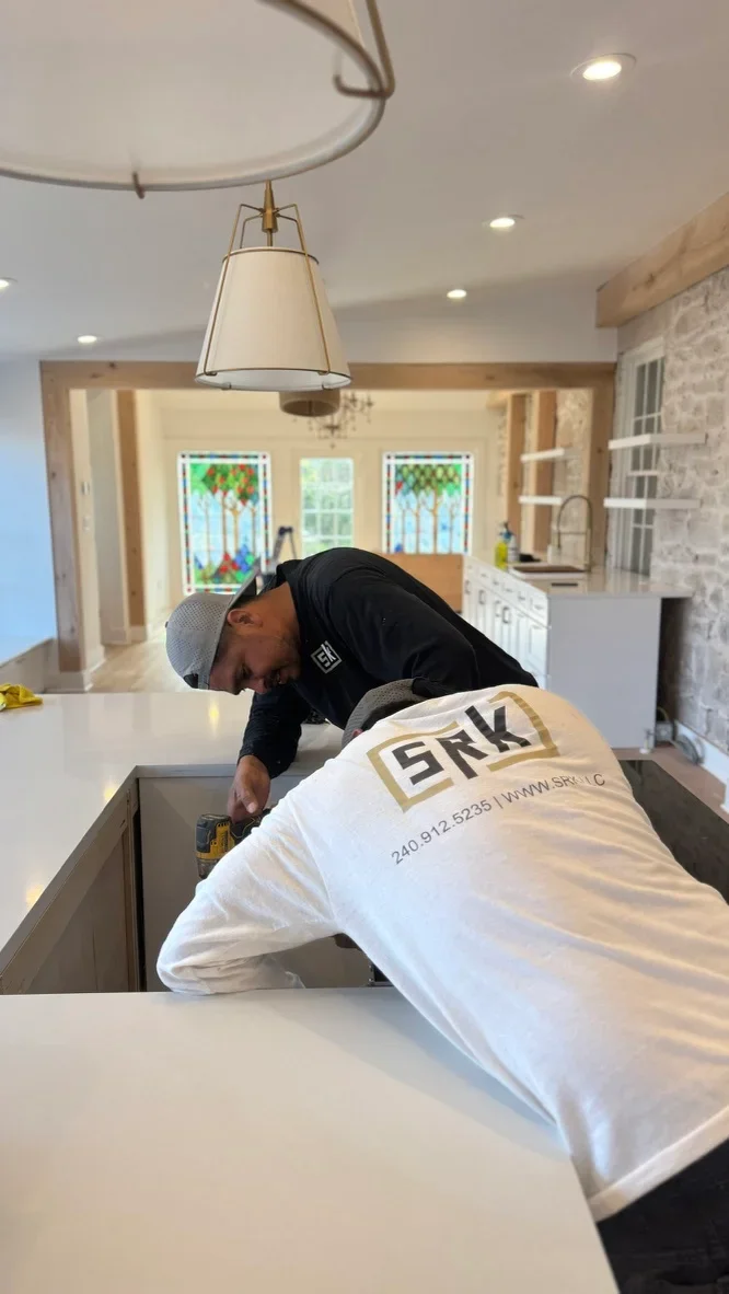 Contractor installing custom kitchen island with white countertop and integrated appliances
