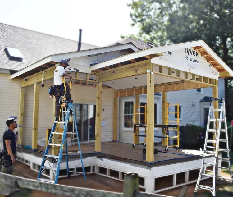 Covered patio addition under construction with timber framing and roof installation in progress